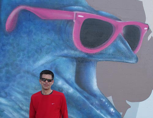 Läufer mit Sonnenbrille vor Grafitti eines Fisches mit Sonnenbrille