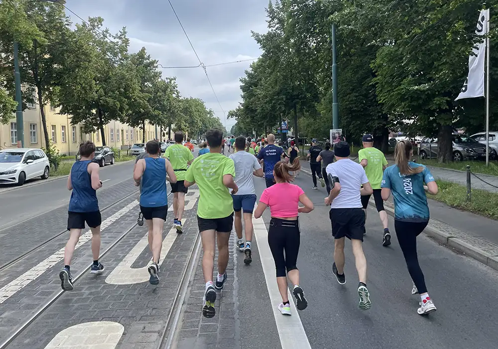 Läuferinnen und Läufer des 10 km Schlösserlaufs in potsdam auf der Strecke (Straße mit Tram-Schienen)