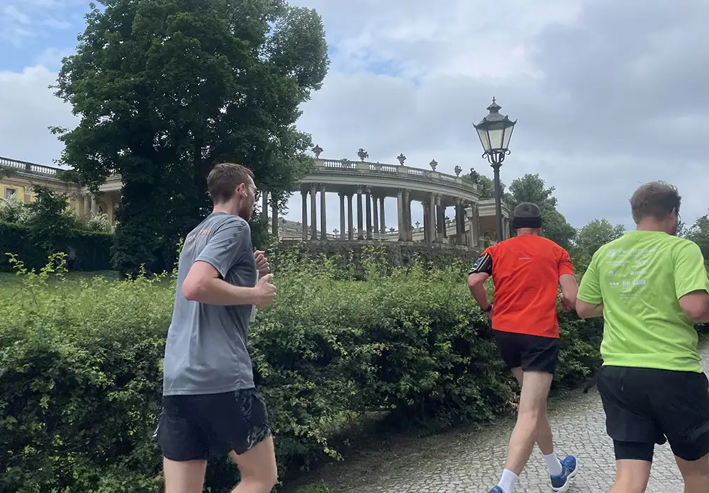Läufer laufen an den Kolonnaden des Ehrenhofs von Schloss Sanssouci vorbei