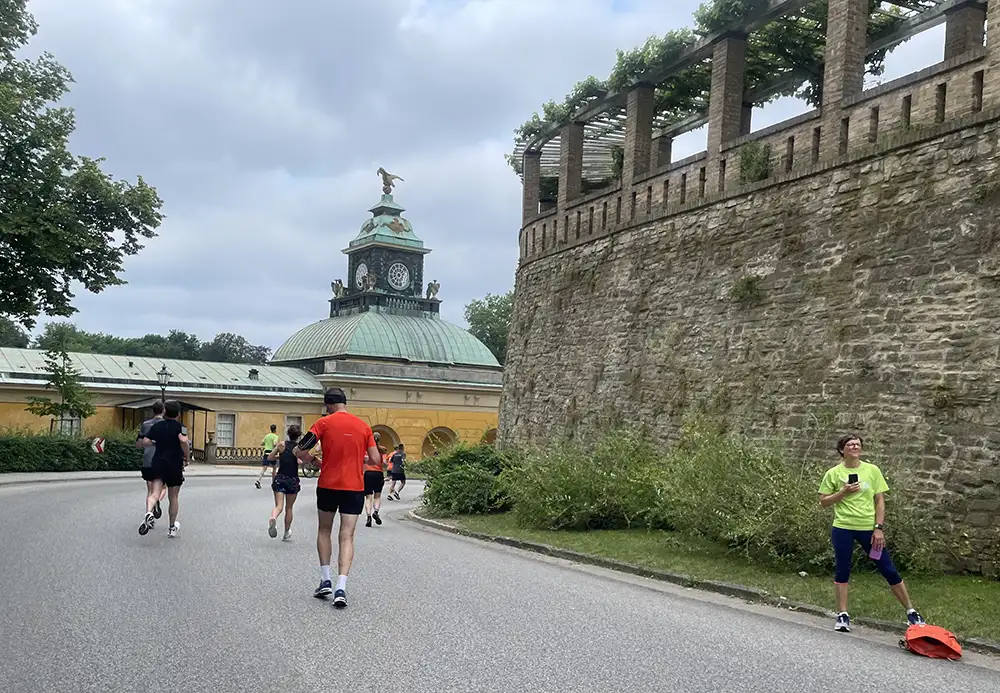 Läuferinnen und Läufer auf leicht abschüssiger Straße mit Blick auf die Neuen Kammern (Orangerie)