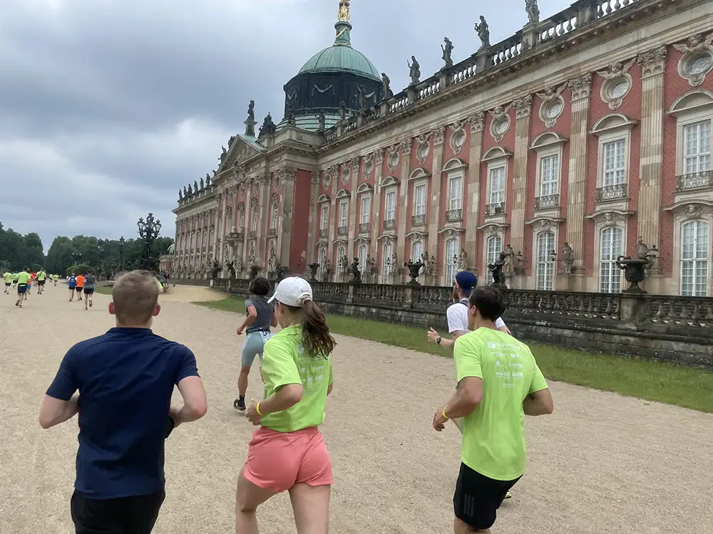 Läuferinnen und Läufer laufen am prunkvollen Neuen Palais vorbei
