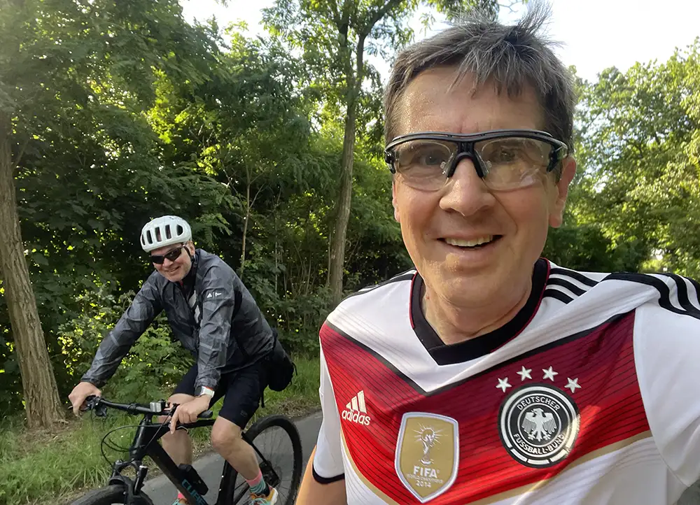 Läufer und Fahrradbegleiter lächeln in Kamera